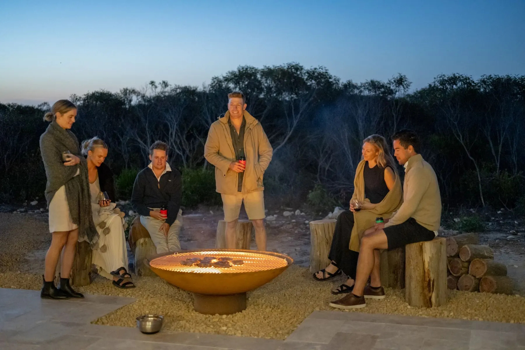 Guests around the firepit on the gravel terrace after dark