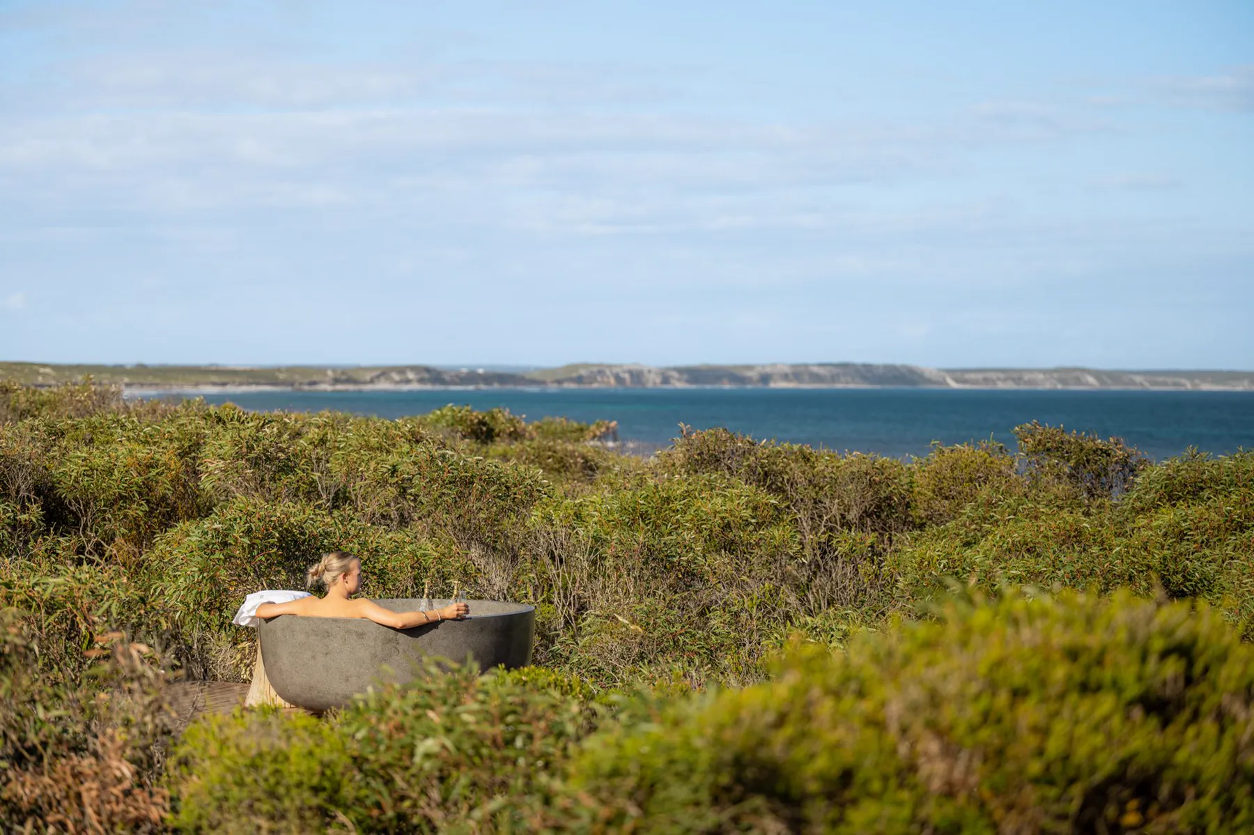 A guest relaxing in the outdoor stone bath overlooking D'Estrees Bay