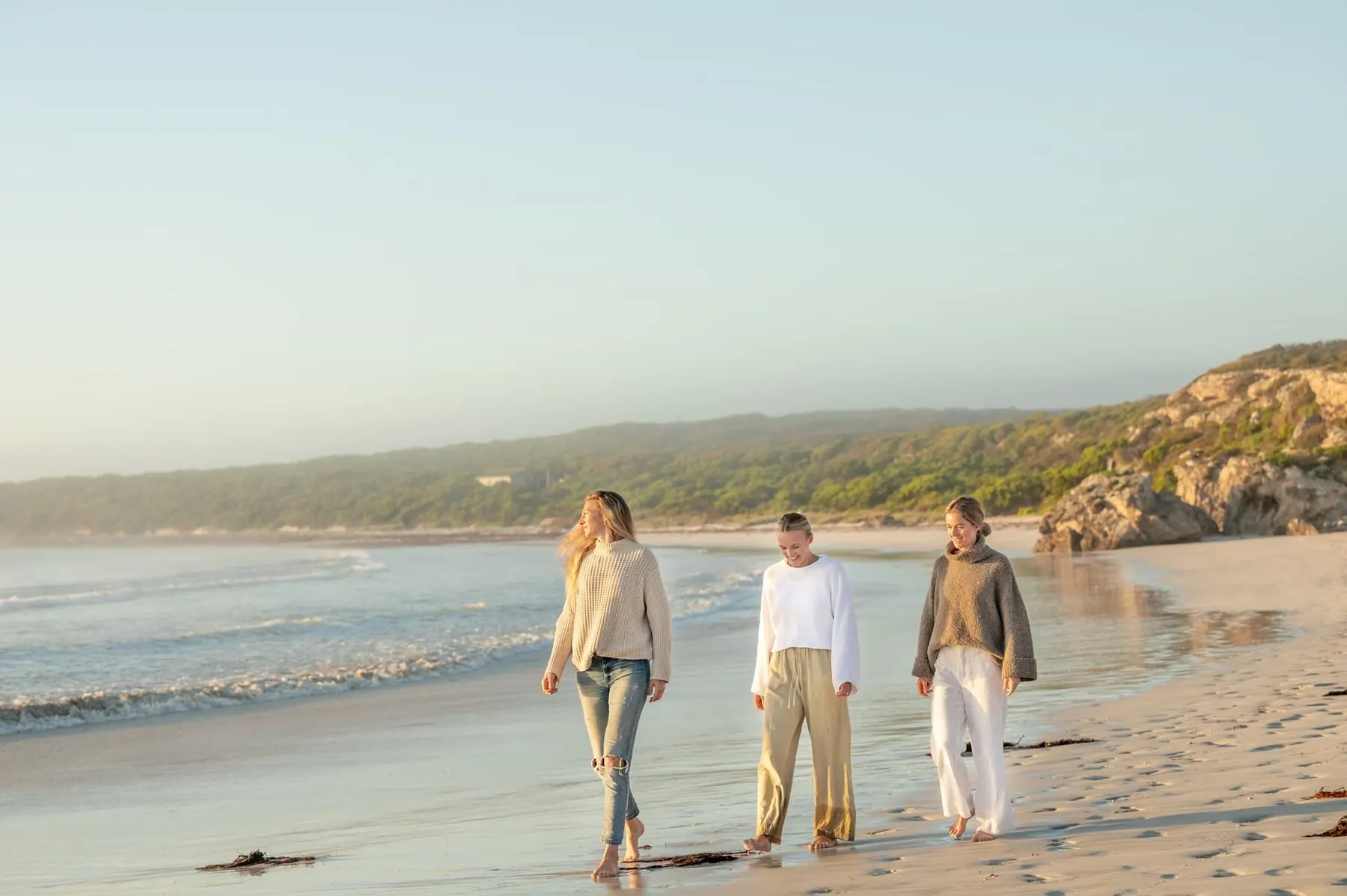 Friends walking a wide empty beach at sunrise