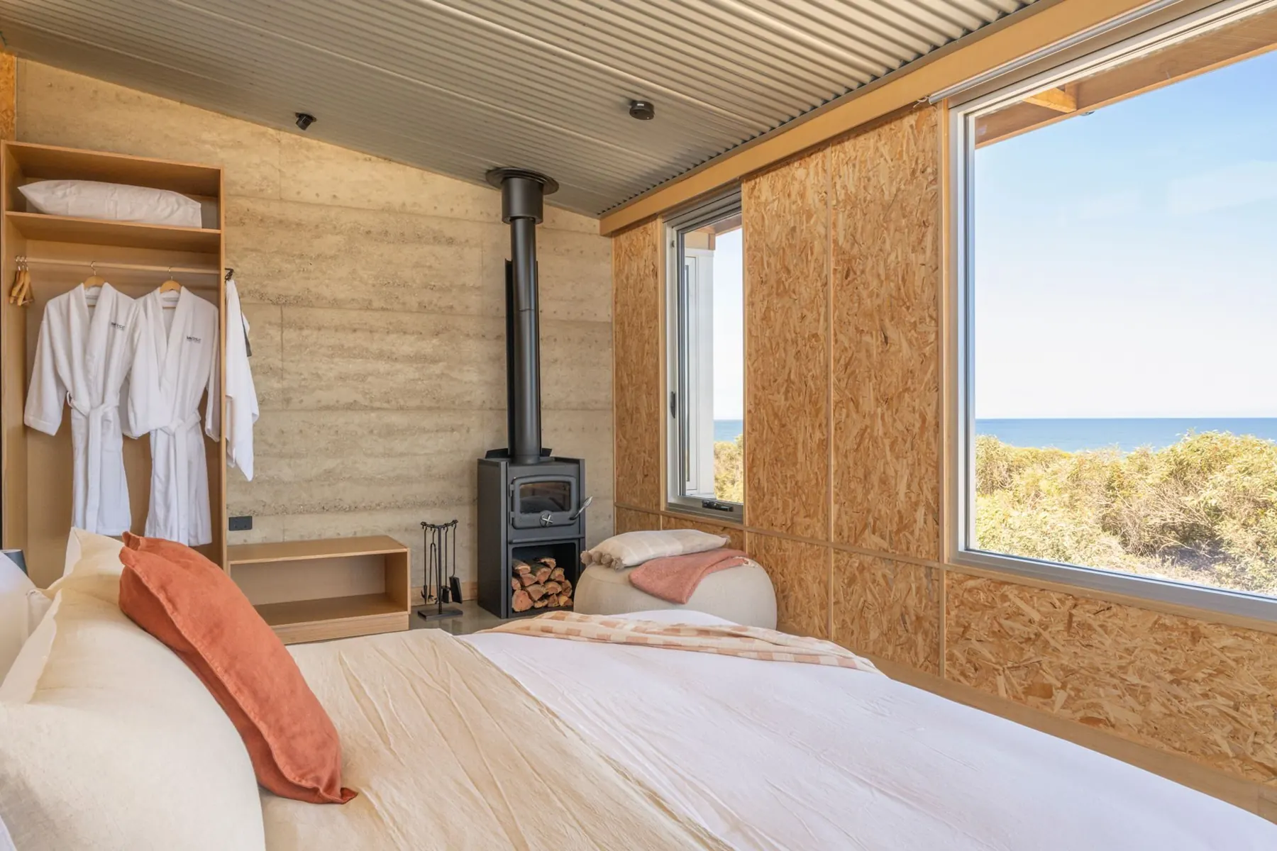 Main bedroom with a slow-combustion fire and a window framing the sea