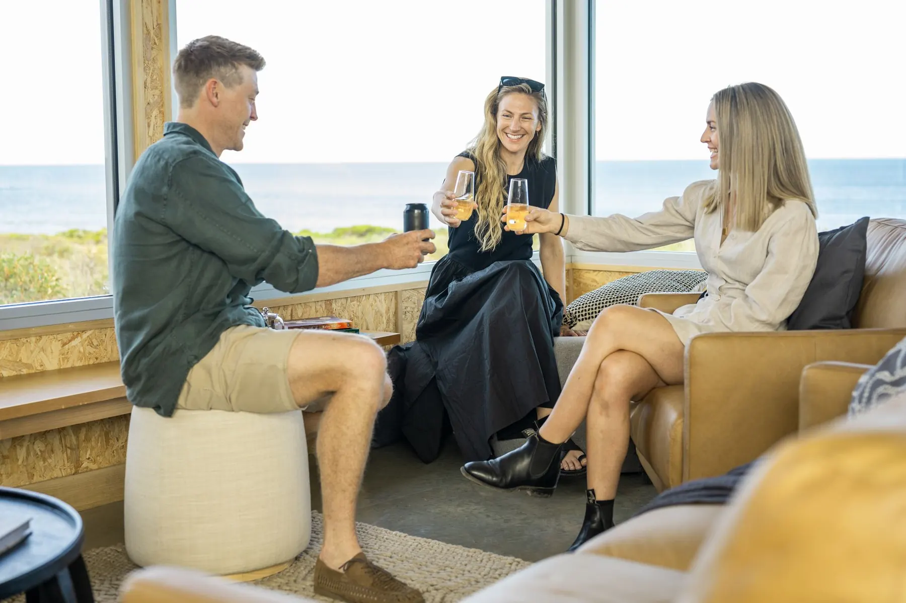 Guests raising a toast in the sunlit lounge with floor-to-ceiling ocean views