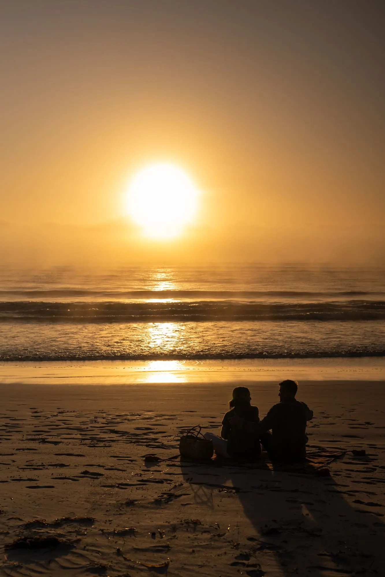 Two guests walking the empty white sand of a Kangaroo Island beach in early light