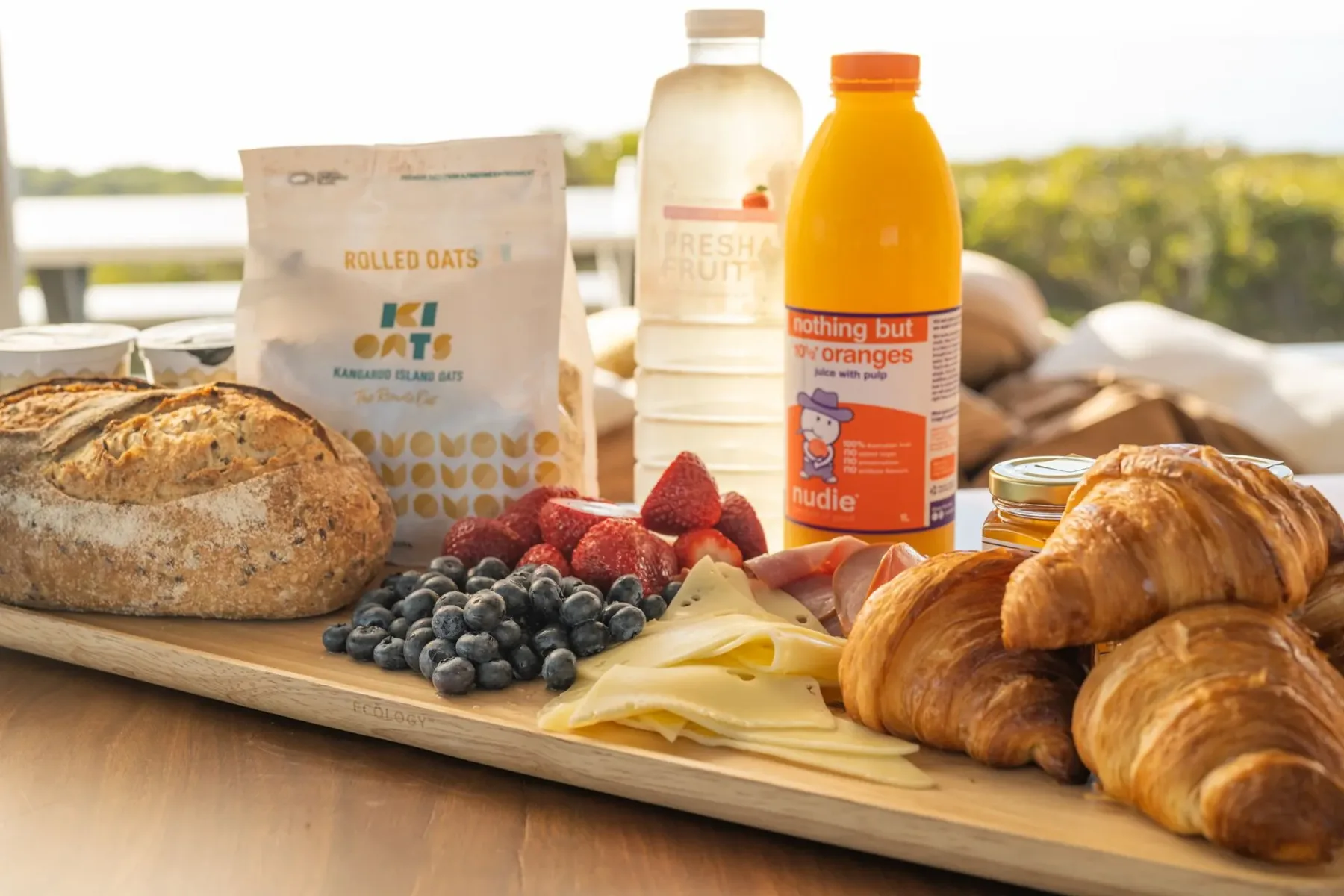 Continental breakfast board with sourdough, croissants, berries, cheese, ham, oats and juice