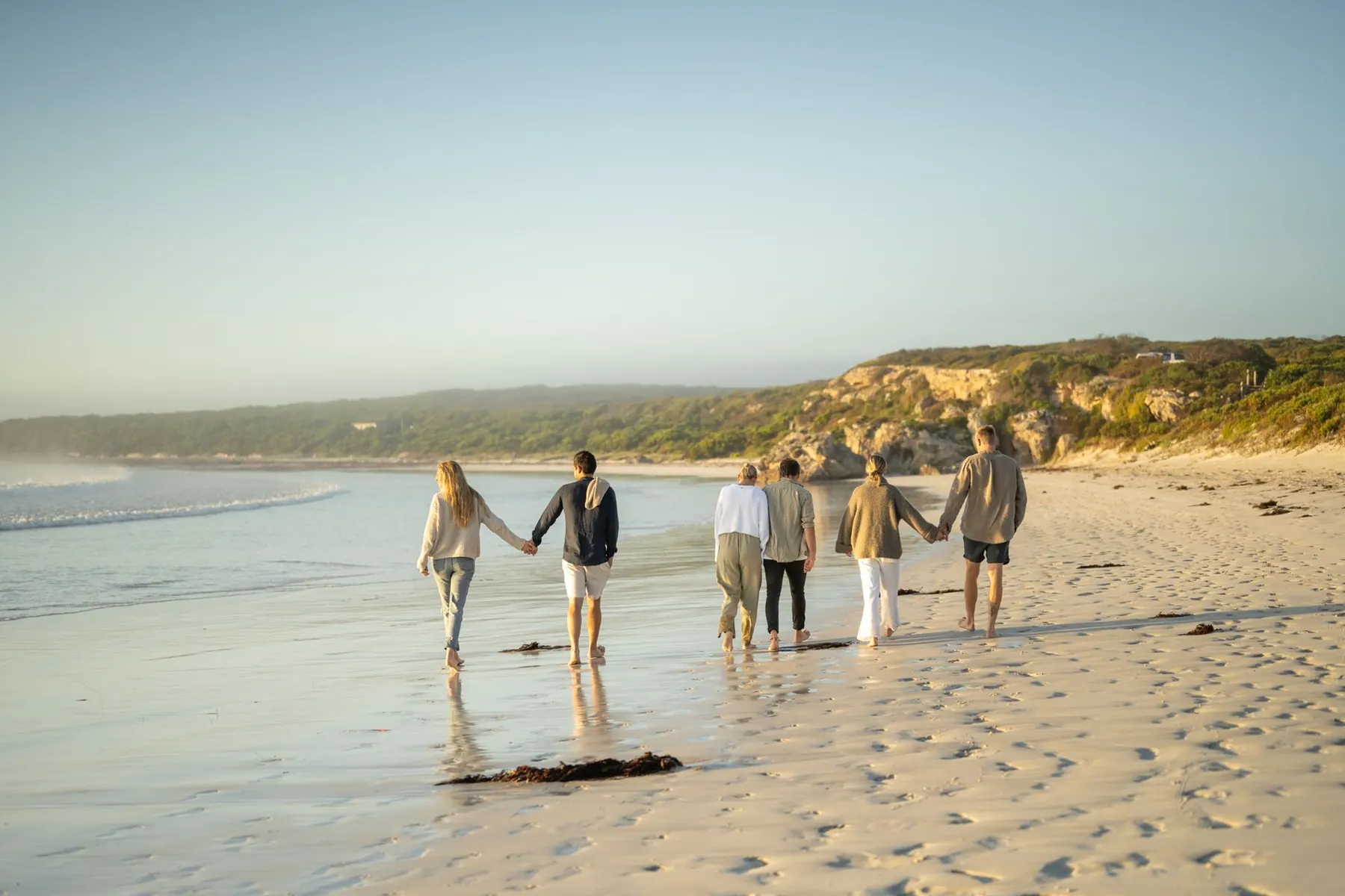 Guests walking a wide empty beach at sunrise